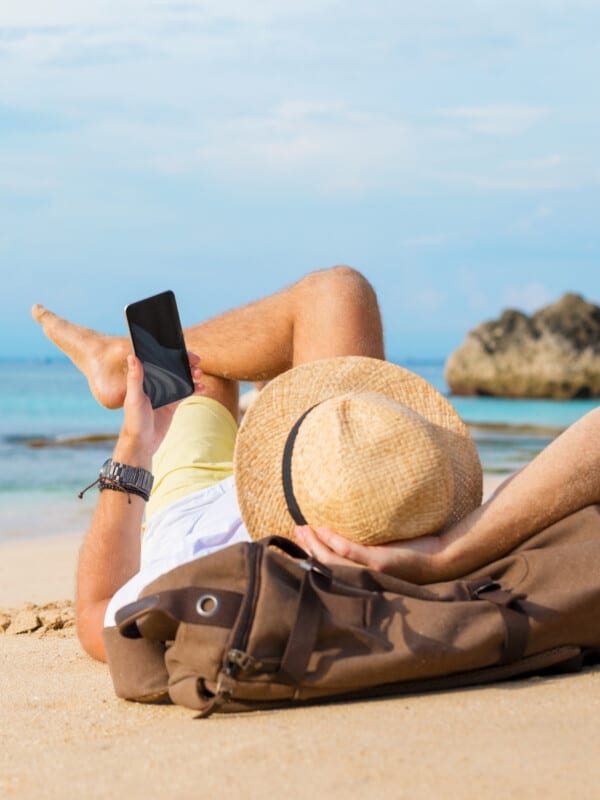 Guy with smartphone lying on the beach.