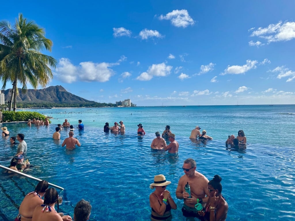 People relaxing in Sheraton Waikiki's adults-only infinity pool with a view of Diamond head and the ocean in the background.