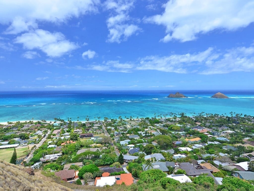 Stunning panoramic views of the turquoise waters of Lanikai Beach which is dotted with palm trees and the Mokulua Islands.