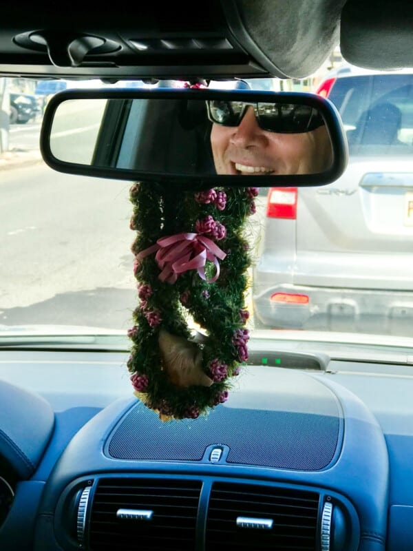 An Uber driver looking through his rearview mirror with a lei draped over it.