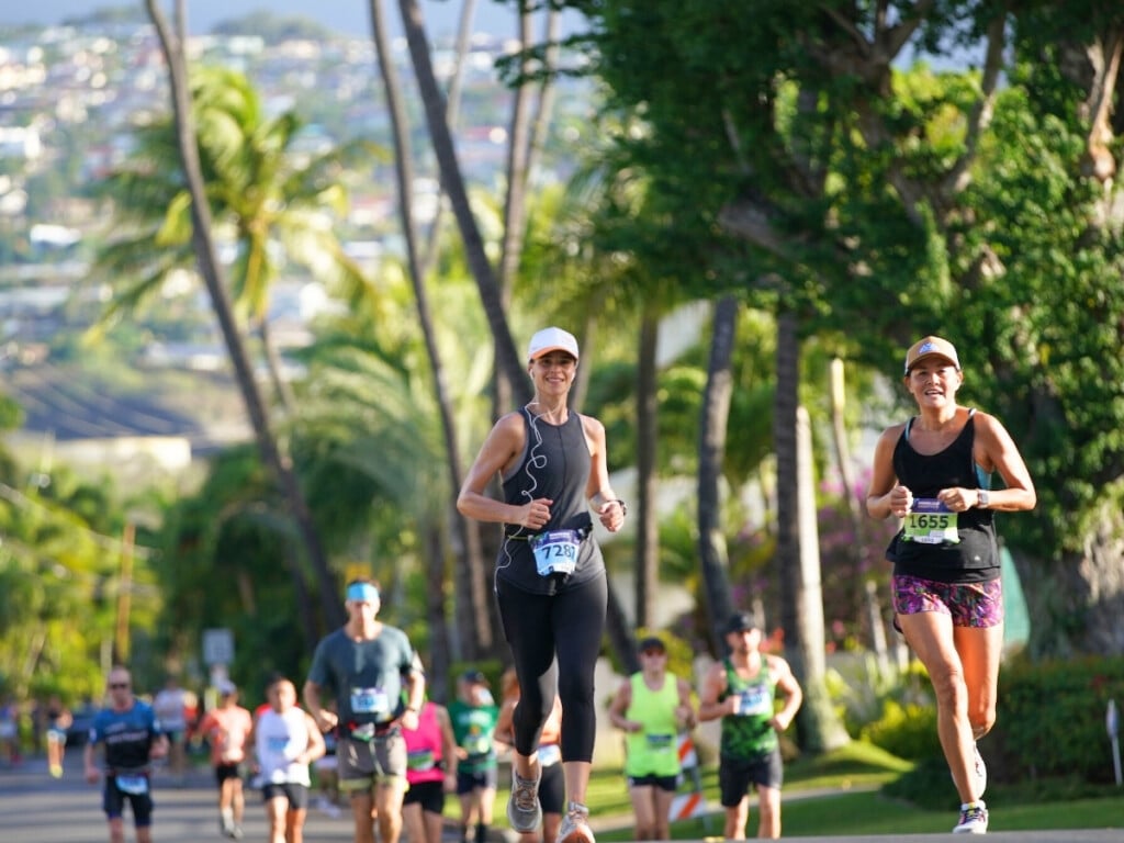 Participants jog through palm tree lined roads at Honolulu Marathon.