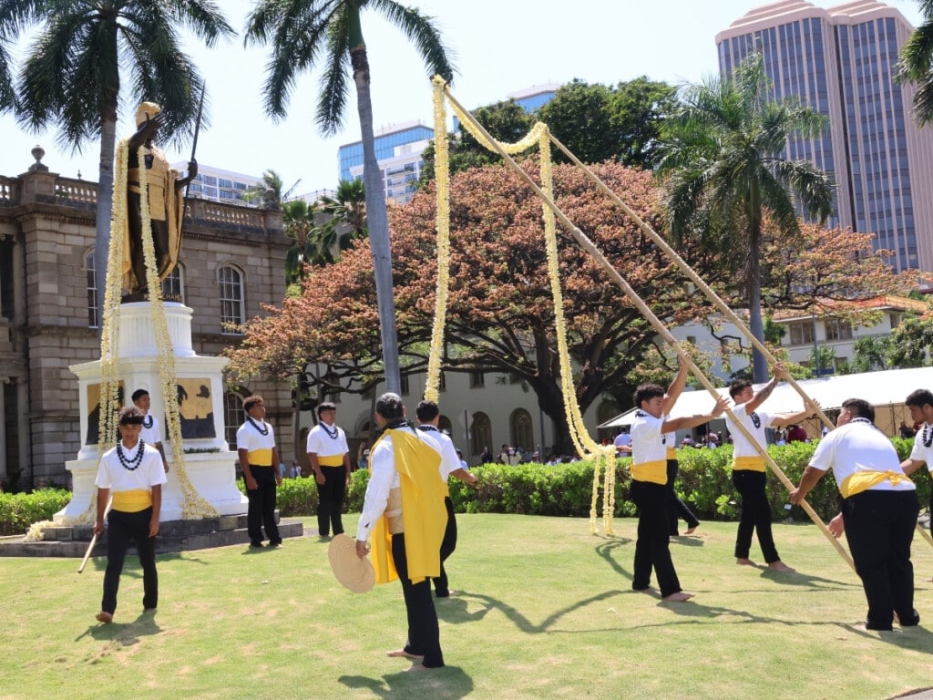 A group of participants carefully drapes long strands of lei over the statue of King Kamehameha during the annual King Kamehameha Celebration Lei Draping in Honolulu. 