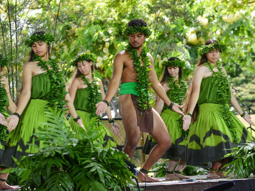 Hula dancers dressed in green attire and tea leaf lei perform on stage at the Prince Lot Hula Festival on O‘ahu.