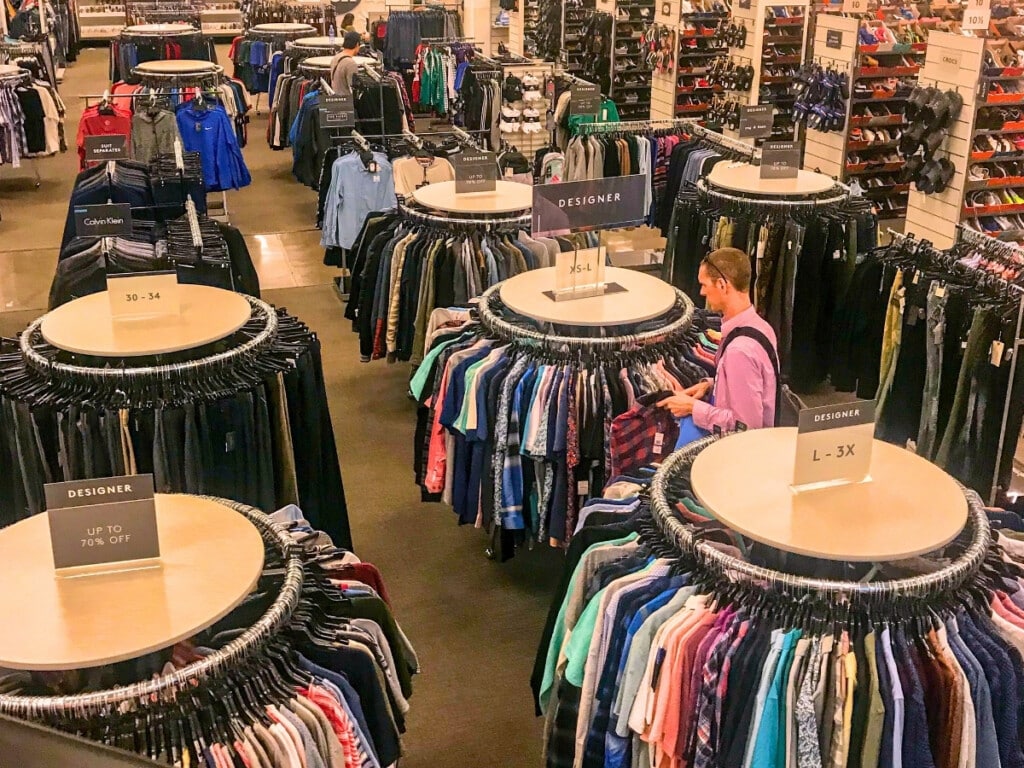 The menswear section of Ward Village Shops featuring racks of designer men's shirts and pants as well as aisles of shoes. 