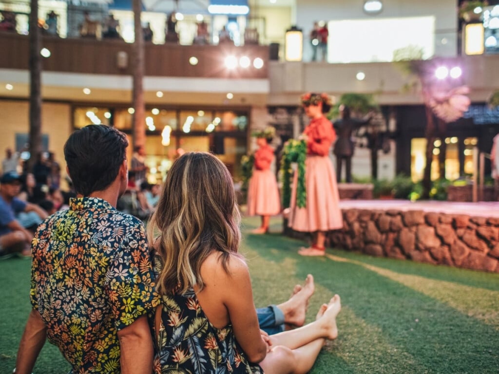 Couple watching the O Nā Lani Sunset Stories Hula Show at International Market Place.