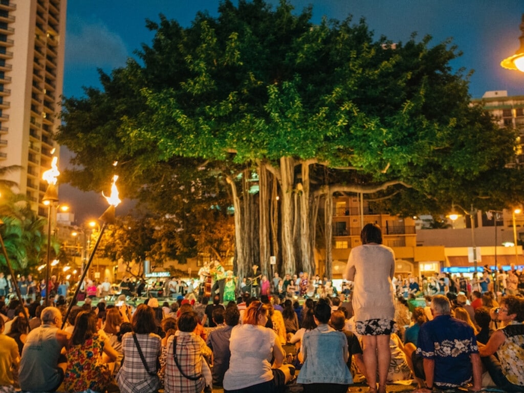 Crowd watching outdoor hula show under the banyan tree at Kūhiō Beach Hula Mound.