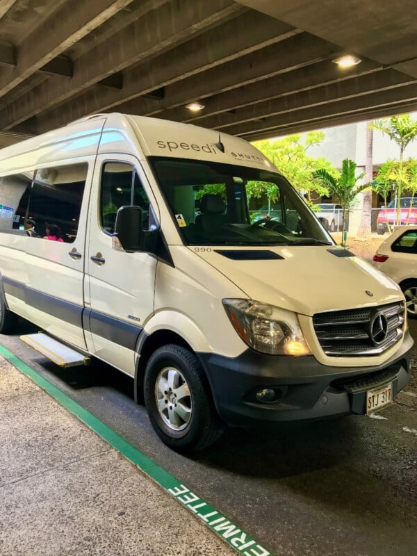 A white Speedi Shuttle van at Honolulu Airport picking up passengers to transfer to Waikīkī.