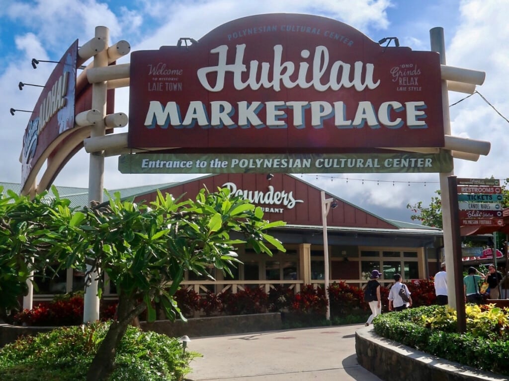 Hukilau Marketplace sign with the Pounders Restaurant in the background at the entrance to Polynesian Cultural Center.