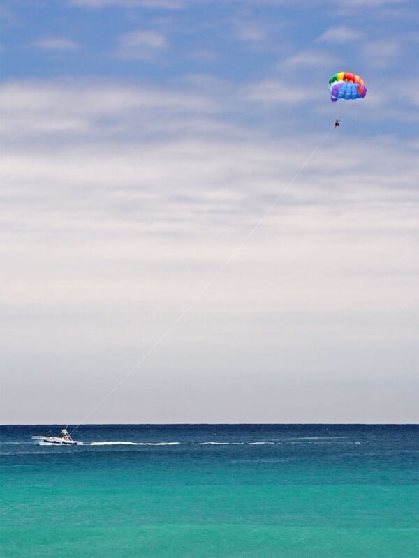 Shot of blue ocean of Waikīkī with a person parasailing in the distance.