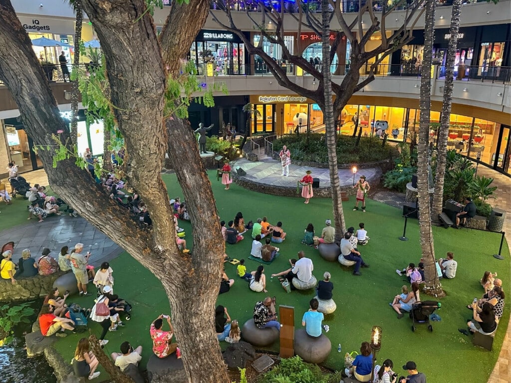 An aerial view over Queen's Court at the International Market Place in Waikīkī when the free O Nā Lani Sunset Stories hula show is starting.