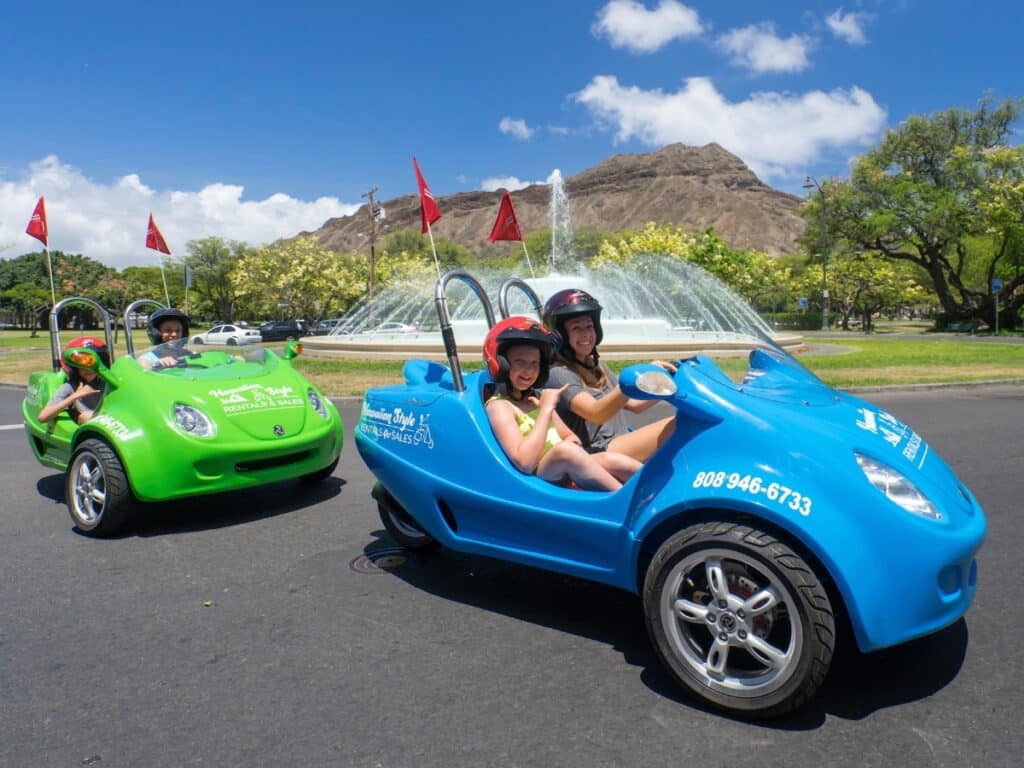 Two scoot coupe driving around the water feature in Diamond Head.