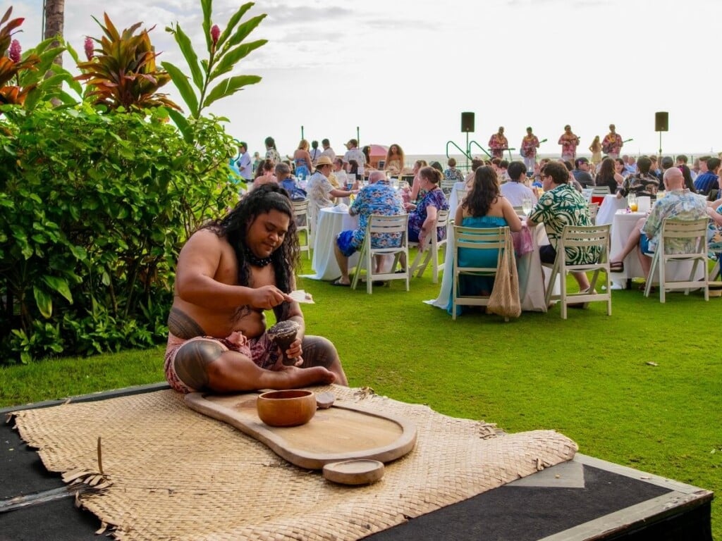 Poi making- a man seating near the bar that pounds taro at ʻAhaʻaina, A Royal Hawaiian Lūʻau.