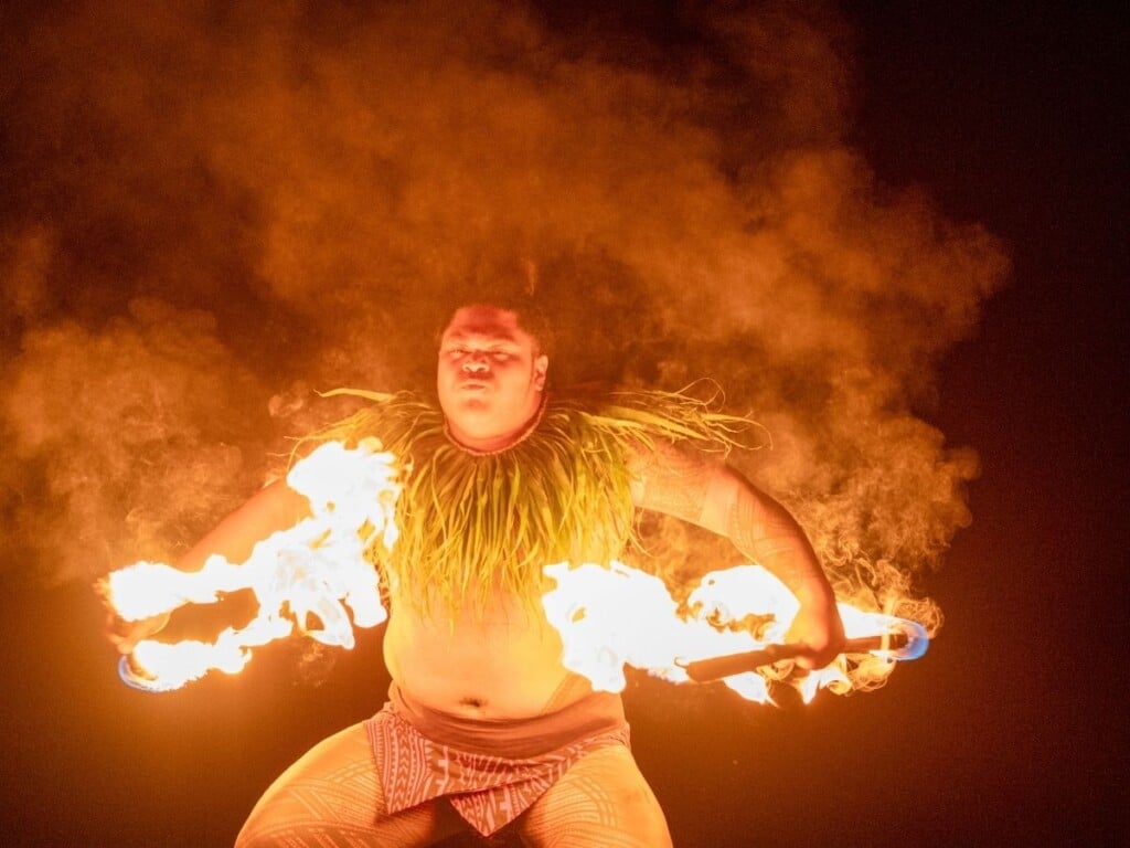 The fire knife dance steals the show in a high-energy performance blending daring flips with spinning metal knives wrapped in blazing cloth at the Ahaʻaina Luau at the Royal Hawaiian.