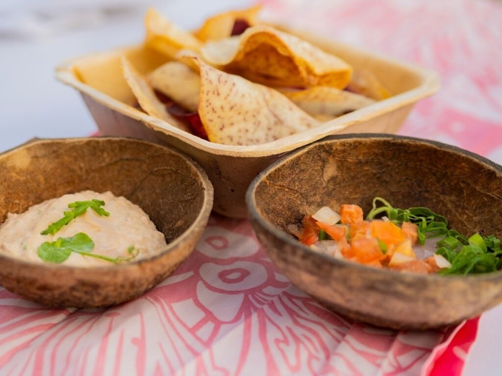 The "table set” that includes Pier 38 Smoked Fish Dip, fish, eggs, pickled sweet onion, sea asparagus, and Poi as well as Lomi Tomato with salmon, paired with taro, sweet potato, and Maui chips at Ahaʻaina Luau at the Royal Hawaiian Resort.