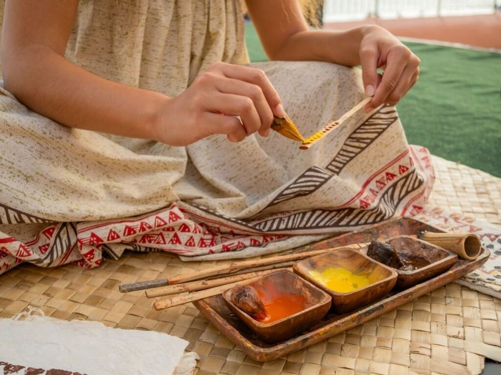 Close of hands painting. Performers bring the culture to life with demonstrations of local art and handiwork at ʻAhaʻaina, A Royal Hawaiian Lūʻau.