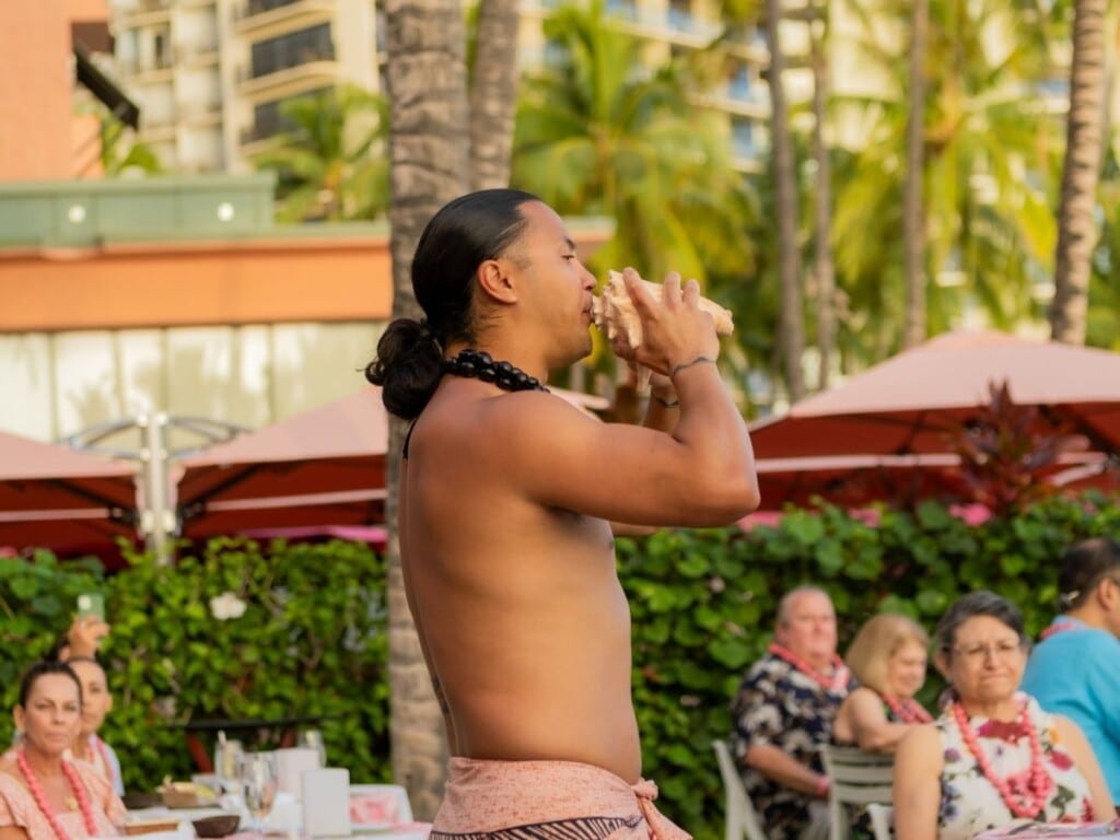As the sun dips below the horizon in Waikīkī, there is a conch shell call, or "pu," signaling the beginning of the feast at ʻAhaʻaina, A Royal Hawaiian Lū‘au.