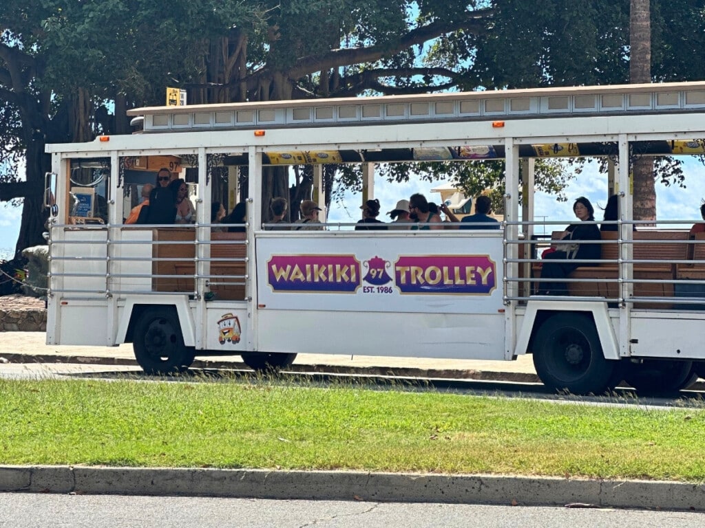 A white Waikiki Trolley traveling past Waikīkī Beach, Hawaiʻi.