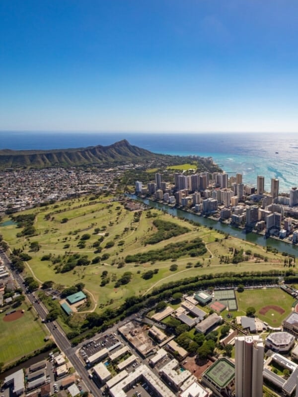 Aerial shot of Ala Wai Golf Course with Waikīkī city and Diamond Head in the background.