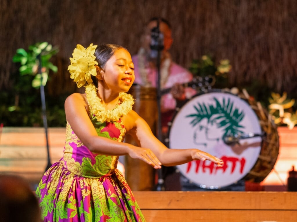 A keiki (child) hula dancer bring joy to the stage with a bright smile and lively performance the Pāʻina Waikīkī Luau.