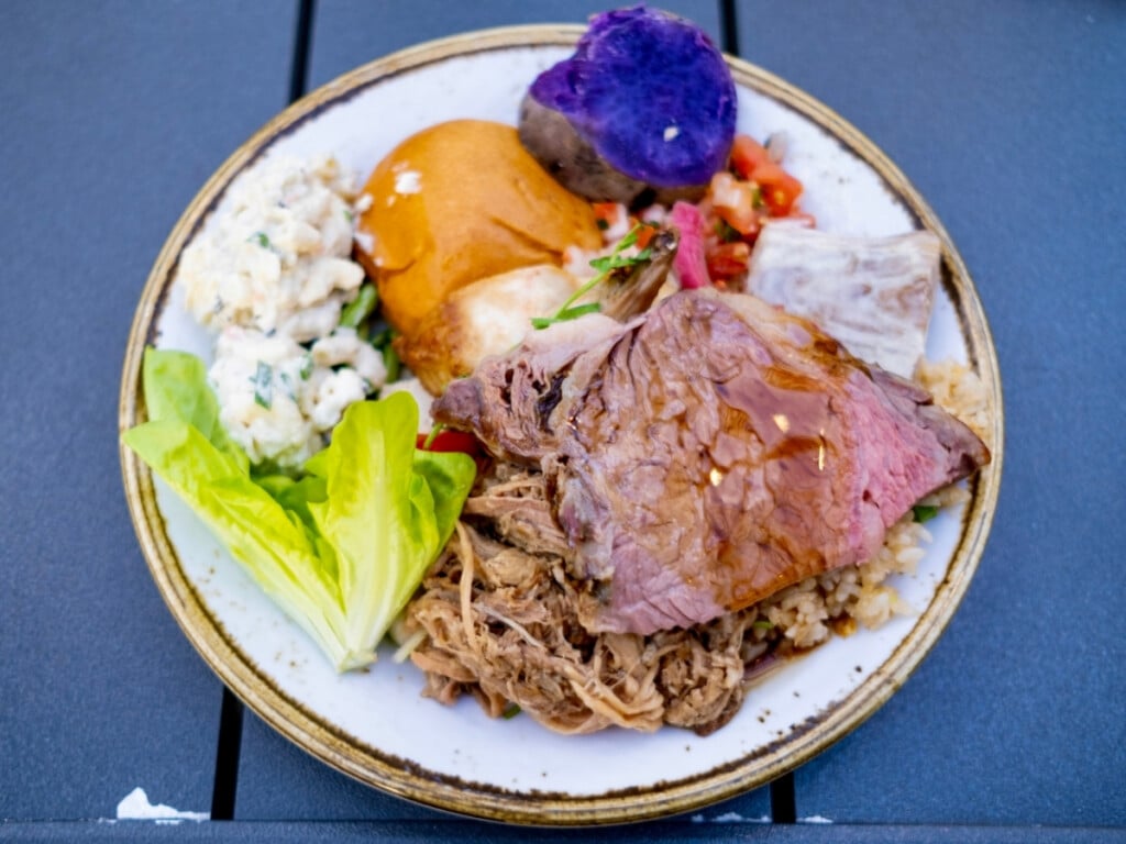 Plate of food in filled with Hawaiian cuisine from the buffet including poi, kalua pork and taro at Pāʻina Waikīkī Luau.