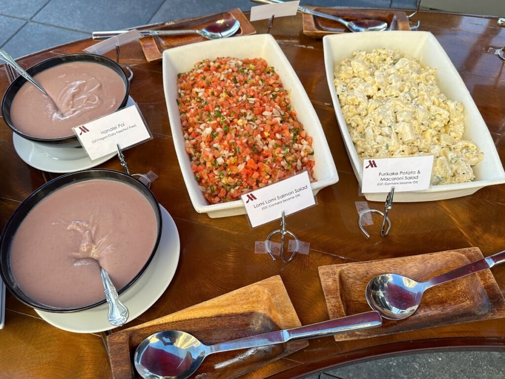 Lomi Lomi Salmon Salad, Furikake Potato & Macaroni Salad & Hanalei Poi on a wooden buffet table at Pāʻina Waikīkī Luau.