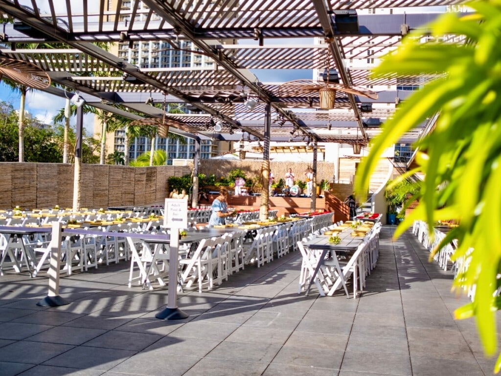 The setting of Pāʻina Waikīkī Lūʻau before the show has begun deaturing long white tables and chairs.