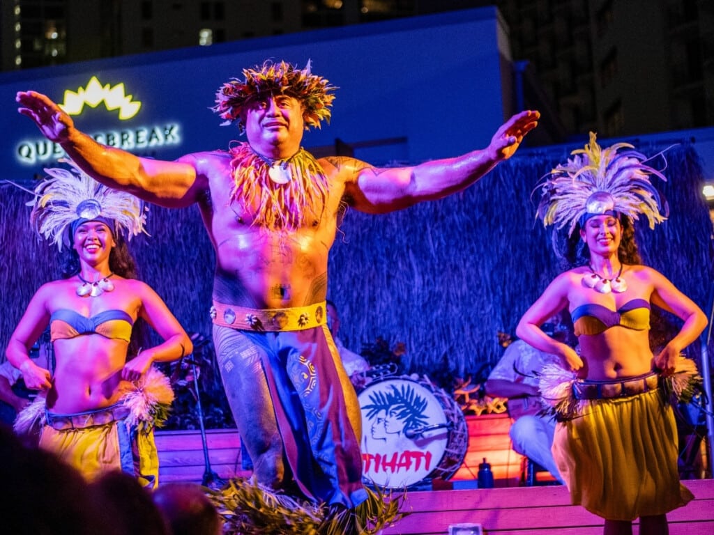 Tahitian dancers perform Ori in colorful costumes adorned in feathers and shells at Pāʻina Waikīkī Luau.