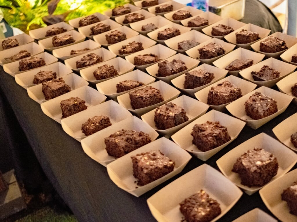 Several portions of Mac Nut Brownies sitting on a black table at the Queens Waikiki Luau.