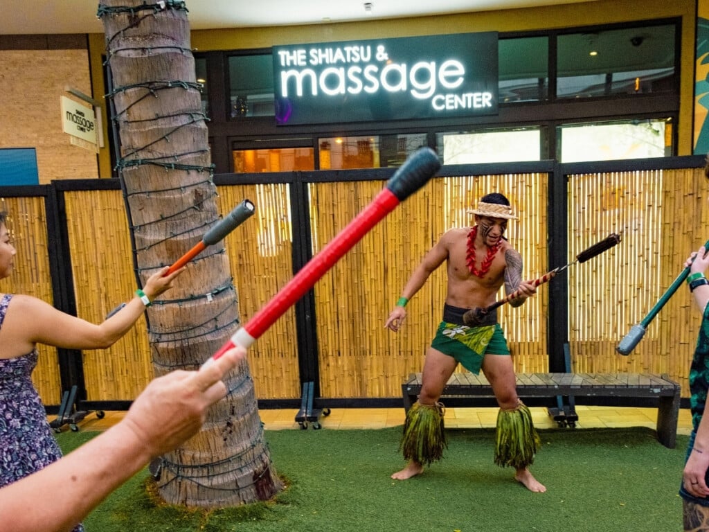 Performer provides interactive cultural demonstration on the art of fire-stick twirling at the Queens Waikiki Luau.
