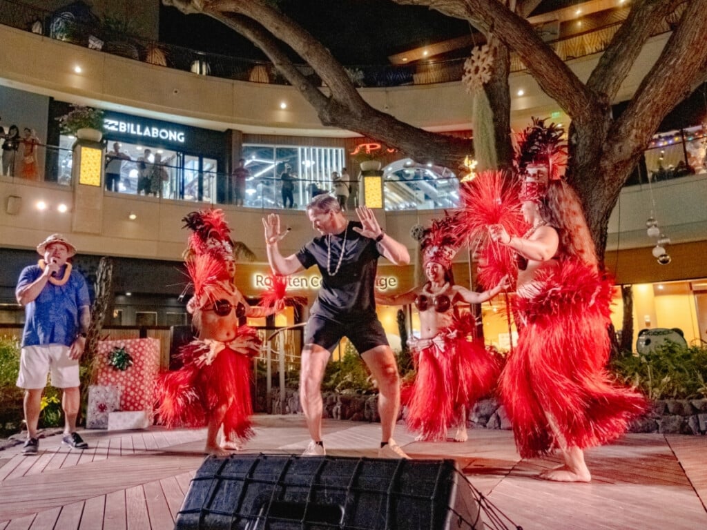 Audience member participates in a hula performance lead by dancers at the end of the show at the Queens Waikiki Luau.