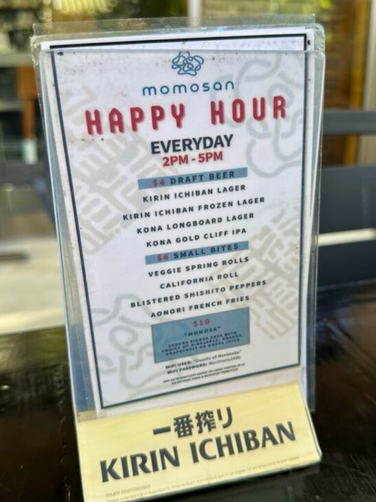 The Happy Hour prices at Momosan Waikiki next to a glass of Kirin Ichiban Frozen Lager.