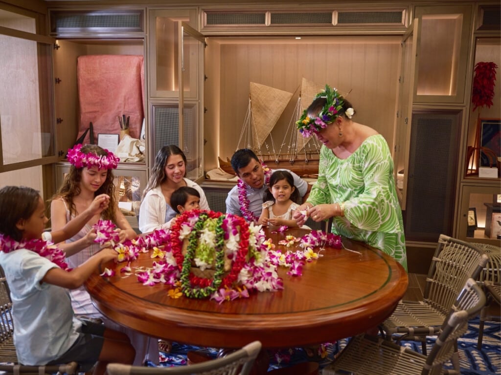 A family taking a floral lei making class at Aʻo Cultural Center at OUTRIGGER Reef Waikiiki Beach Resort.