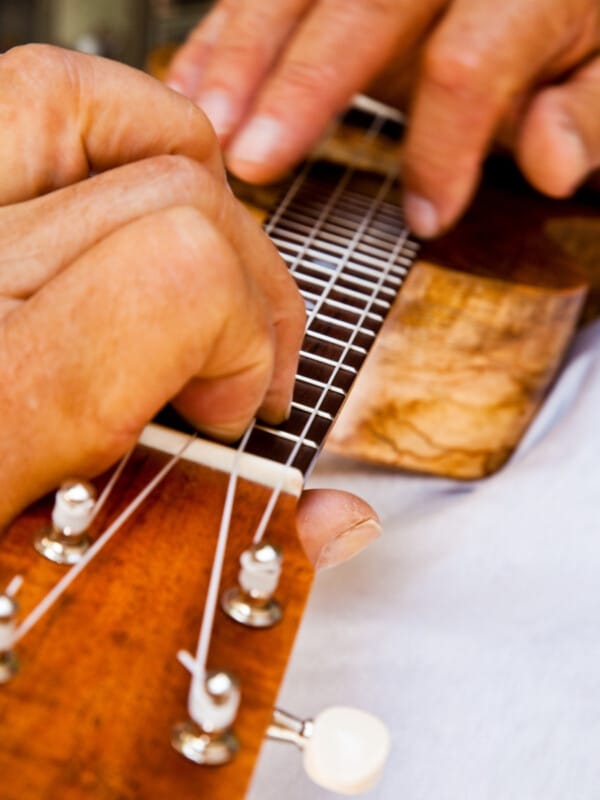Close up of hands strumming a ʻukulele.