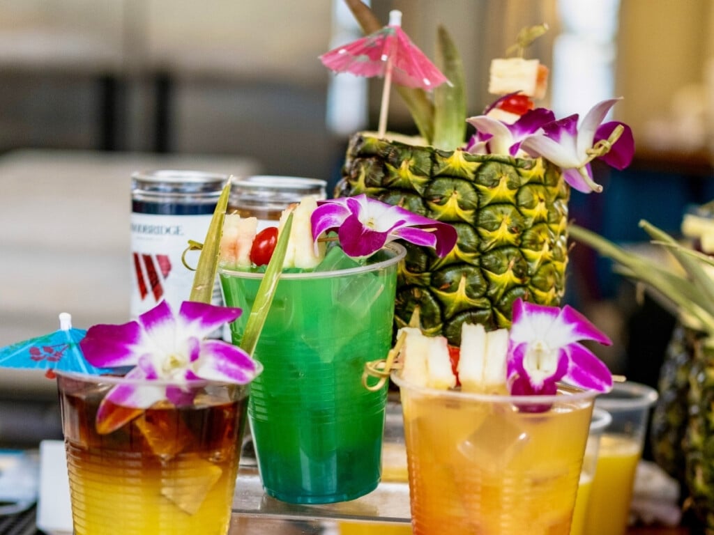 Cocktails at Ka Moana Luau, including a vibrant Blue Hawaii, Mai Tai and Ka Moana Pineapple garnished with bright purple orchids.