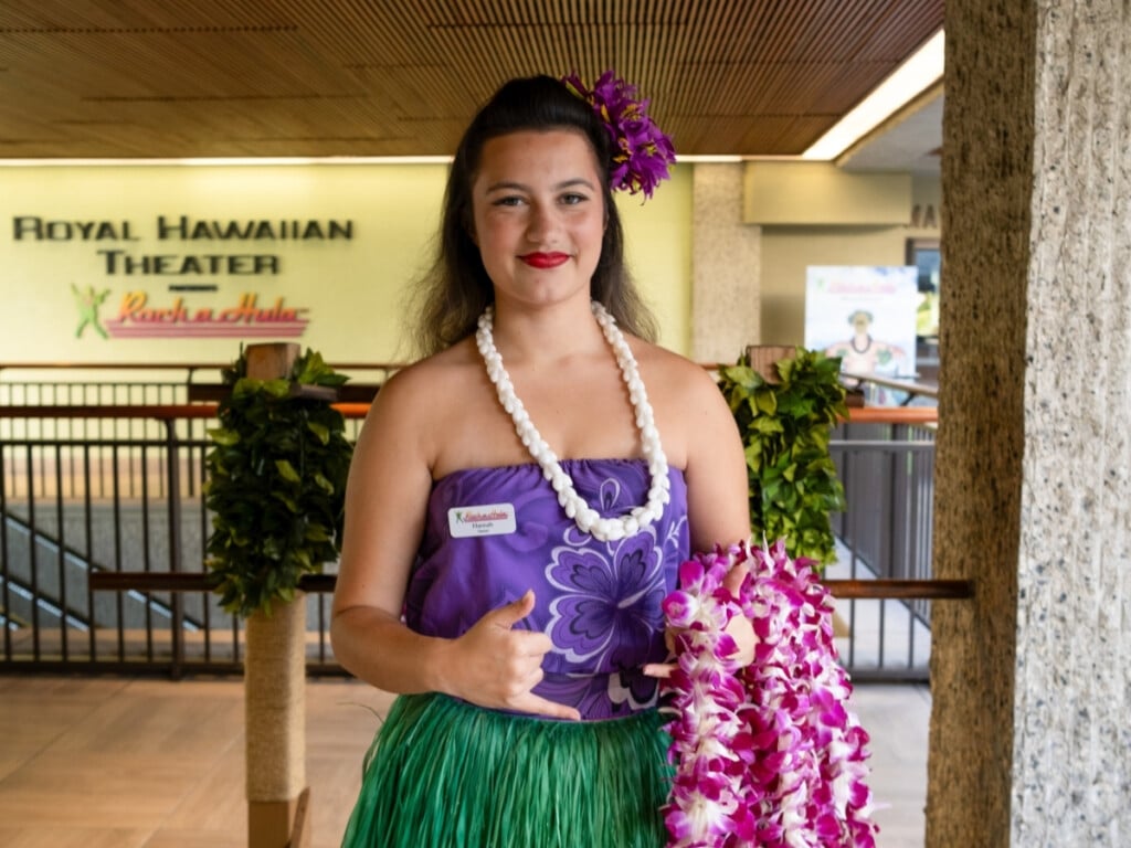 Friendly staff member holding fresh orchid lei at the Waikiki Luau Buffet & Rock-A-Hula Show.