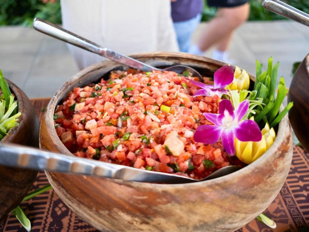 A bowl of fresh homemade Lomilomi Salad garnished with colourful flowers from the Waikiki Luau Buffet & Rock-A-Hula Show.