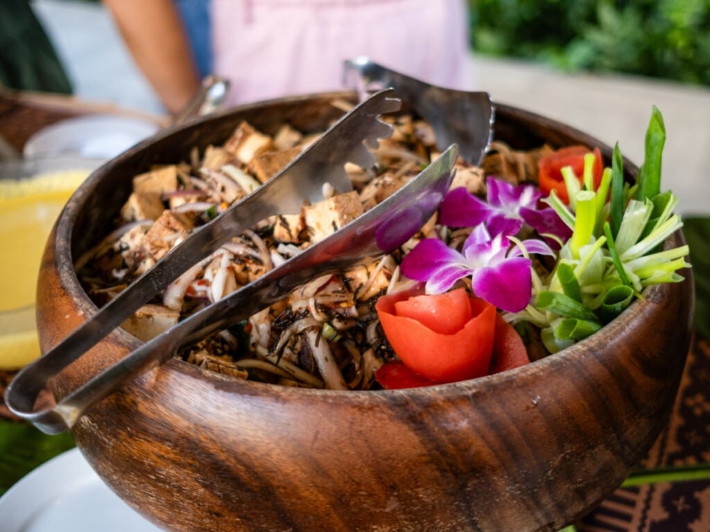 The Limu Tofu Poke in a wooden bowl and garnished with colorful flowers at Waikiki Luau Buffet & Rock-A-Hula Show.