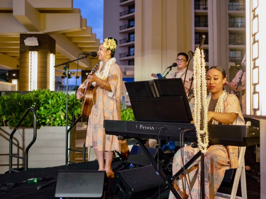 Band performs on stage at the Nā Lei Aloha Waikīkī lūʻau in Oʻahu, Hawaiʻi.