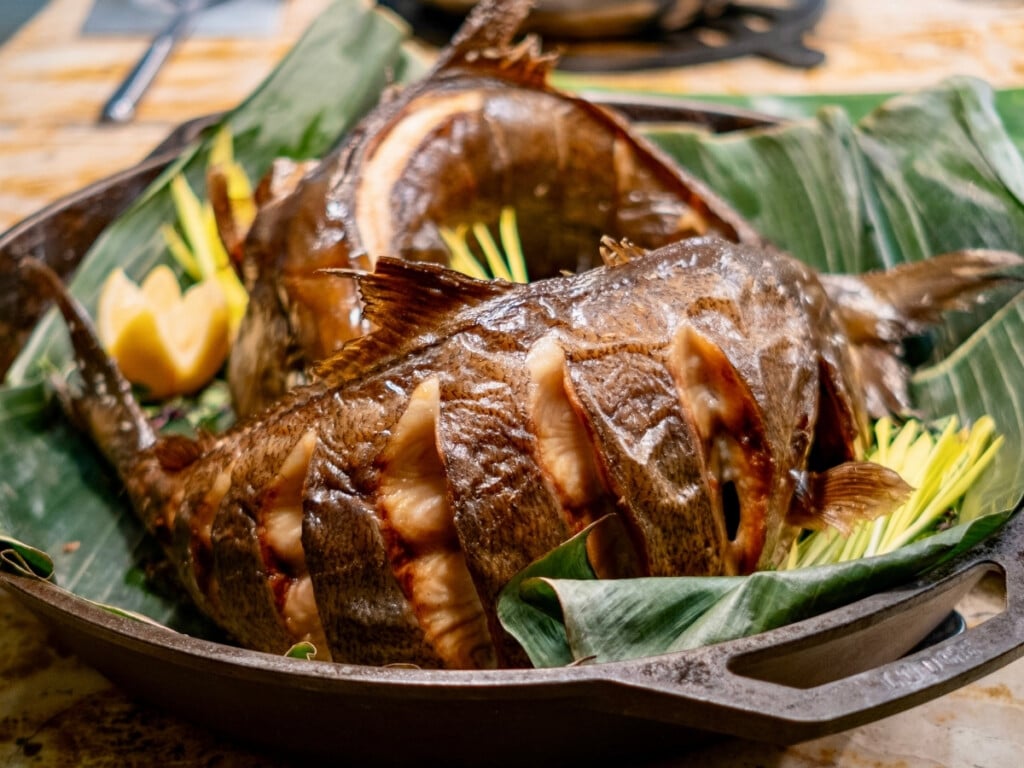 Roasted Kampachi fish on a bed of tea leaves, one of the fresh seafood dishes on the Nā Lei Aloha lūʻau buffet line.