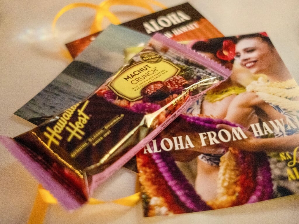 The contents of the goodie bag from Nā Lei Aloha that includes delicious macnut chocolate and three postcards.
