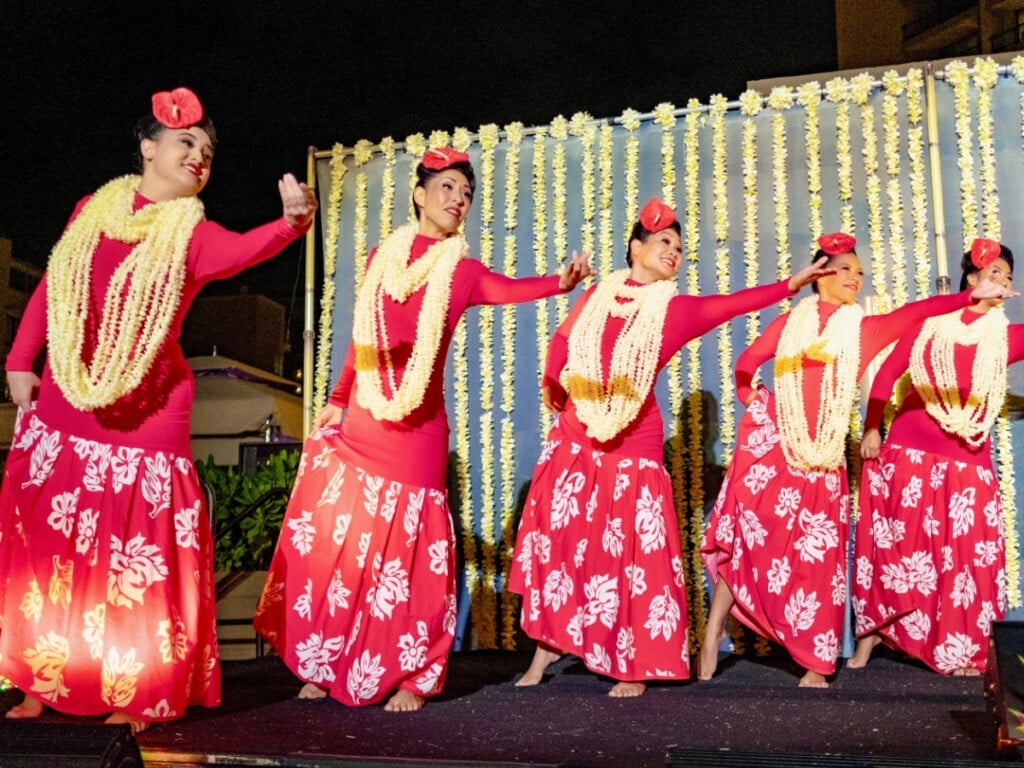 Dancers dressed in red and draped in Fresh flower perform a graceful hula at the Nā Lei Aloha.