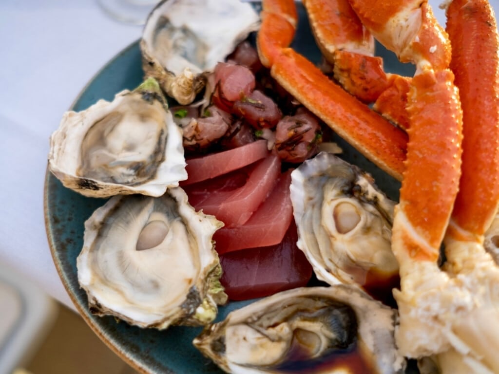 Plate filled with sweet Alaskan crab legs, tender sashimi, top-quality oysters, and flavorful poke made with fresh, locally-caught ahi tuna.