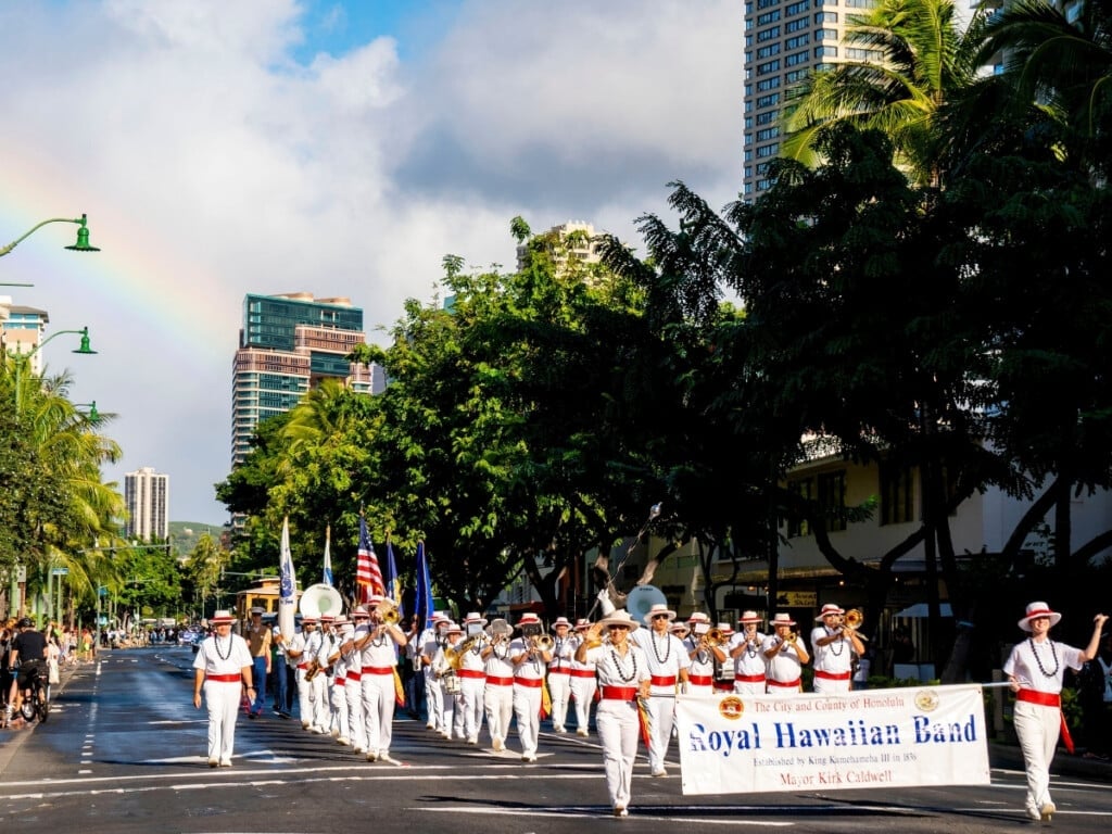 Band marching down Kalakaua Avenue at the Martin Luther King Day Celebration Parade with a rainbow in the background.