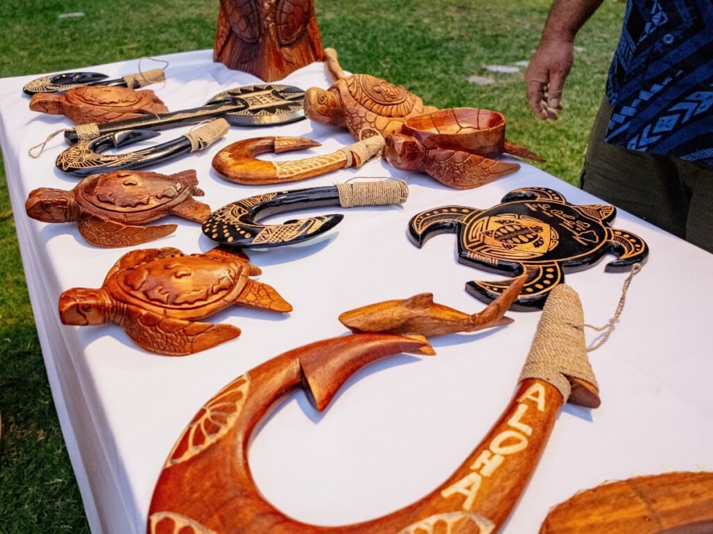 Table displaying wooden Hawaiian ornaments at the Waikiki Starlight Luau: Ocean Lawn.
