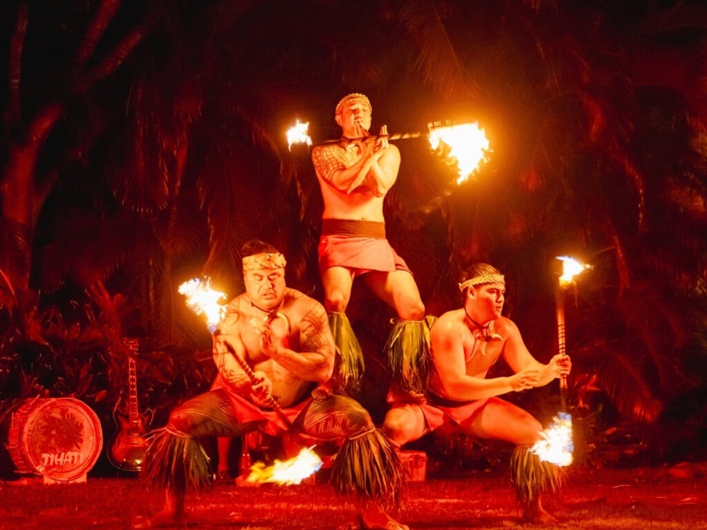 Fire knife dancers performing at Waikiki Starlight Luau: Ocean Lawn twirling fire sticks in a vibrant performance.