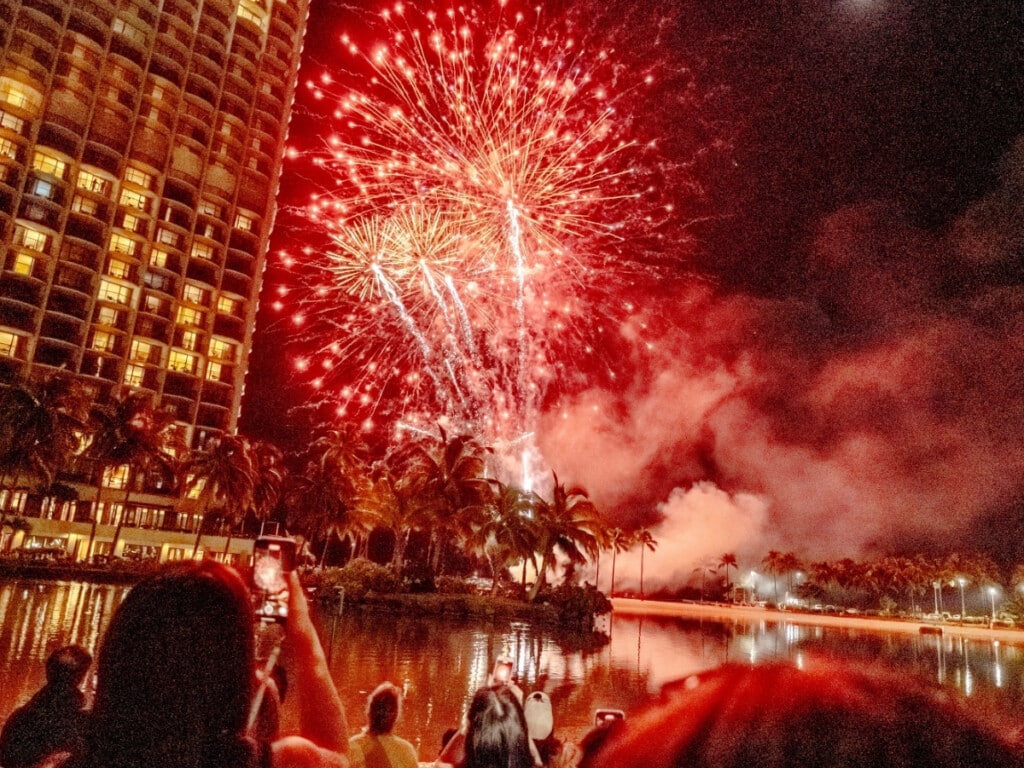 Luau guests watch the Friday Night fireworks above Duke Kahanamoku Lagoon at Waikiki Starlight Luau: Ocean Lawn.