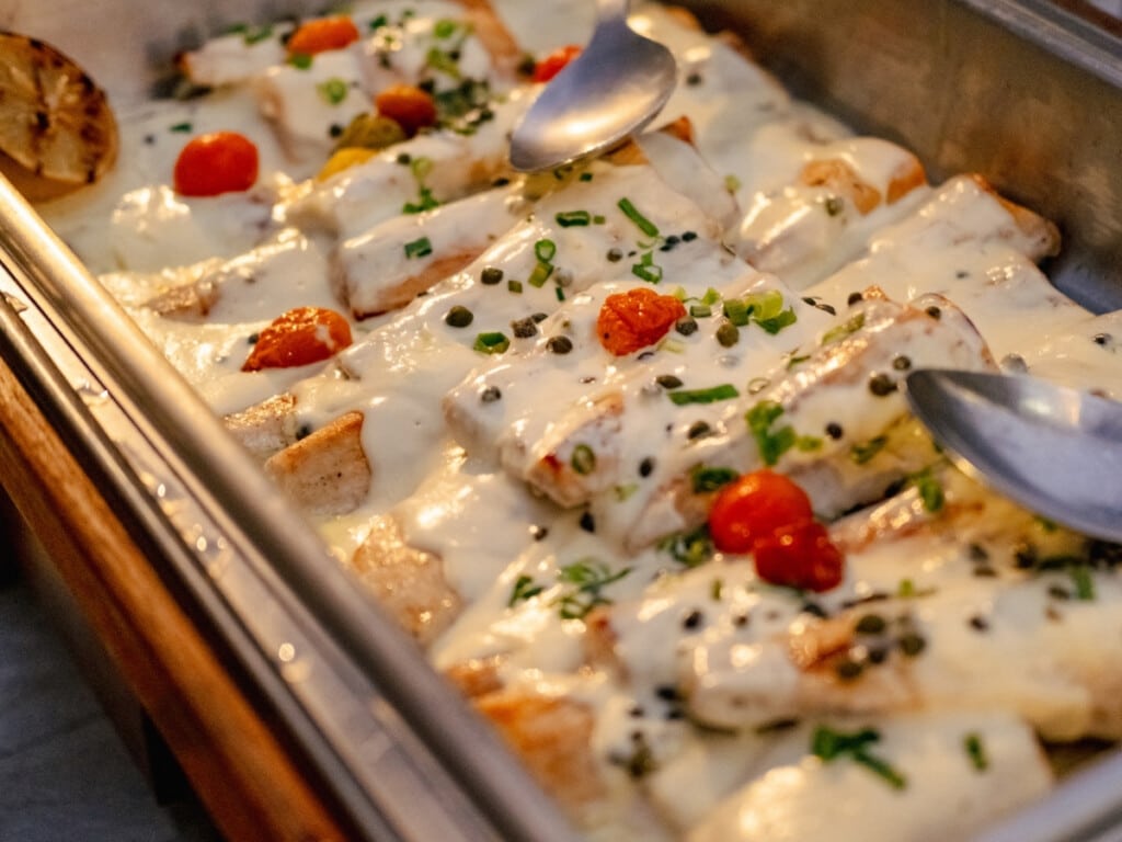 Seared Island Catch with white sauce garnished with tomatoes, pepper corns and spring onions at Waikiki Starlight Luau: Ocean Lawn.