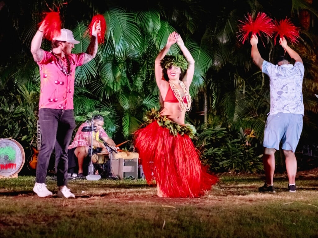 Two audience members participate in a hula performance lead by dancer as a finale of the show.