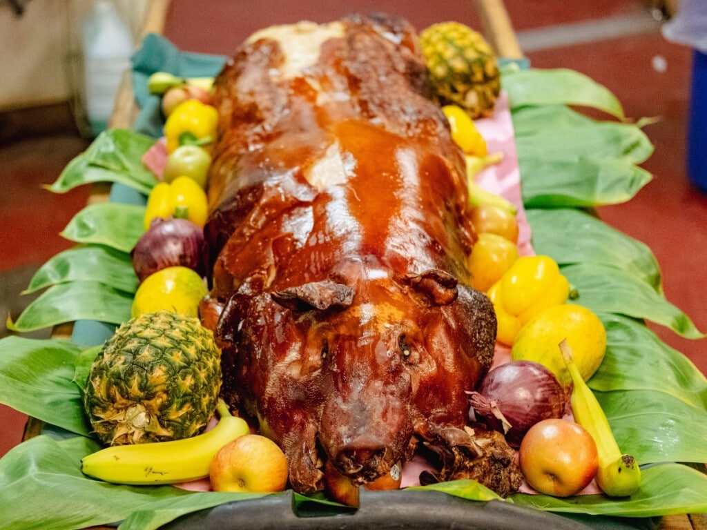 Whole roasted kalua pig on a bed tea leaves and surrounded by colorful fruit and vegetables at Waikiki Starlight Luau: Ocean Lawn.