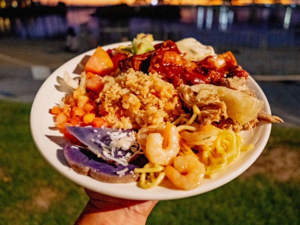 A plate full of food featuring taro, rice, pork and sides from the luau buffet.